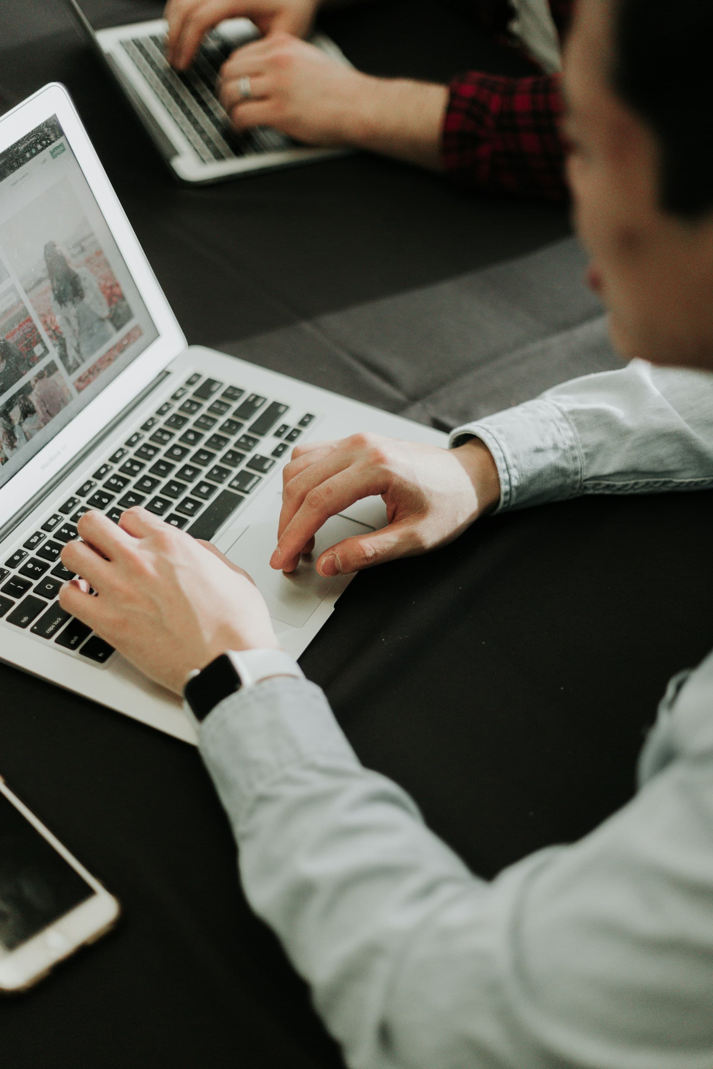 Two colleagues working through a plan side by side on laptops